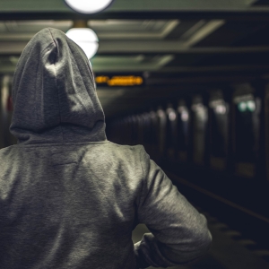 Person wearing a hoodie at a train station
