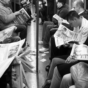 People reading newspapers on public transport